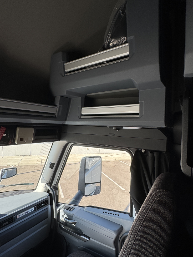 Cab interior of a Mack PR64T76H truck showing overhead sleeper compartments and dashboard area.