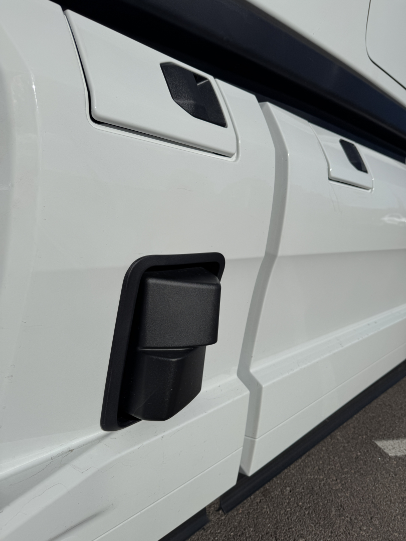 Truck side view showing a black rectangular side marker/wheel well area with white body panels and door outlines.