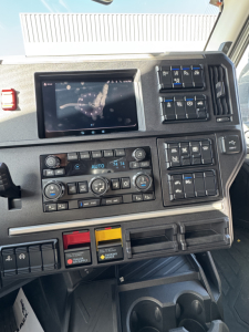Cab interior dashboard of a 2026 Mack PR64T76H showing a touchscreen display, climate controls, and multiple switches in rows.