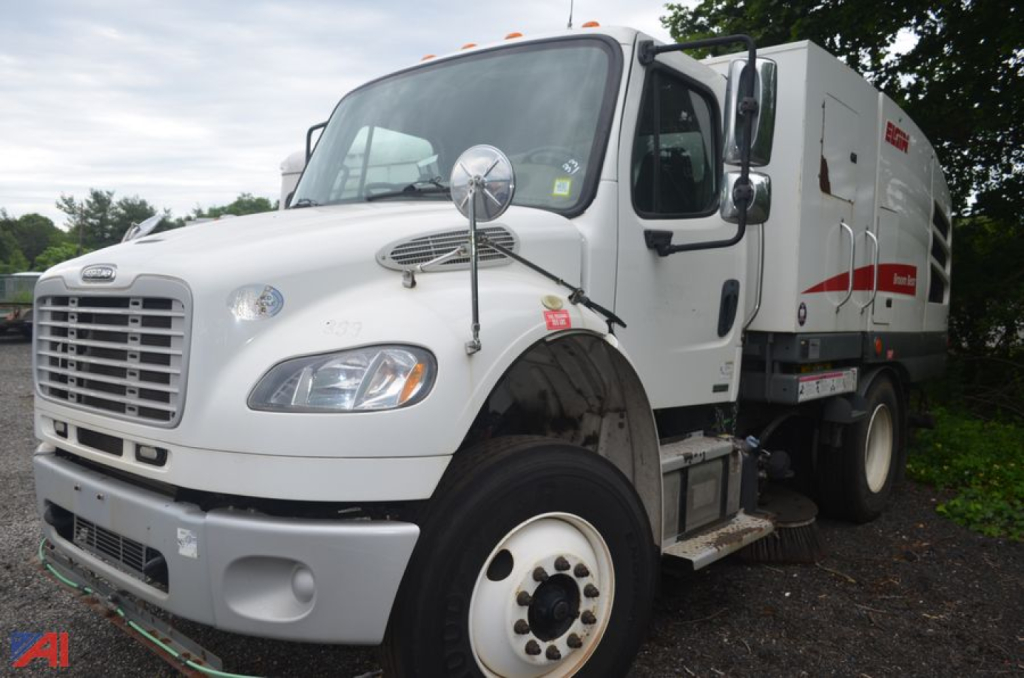 Freightliner M2 106 sweeper truck side view showing cab, large rear body, and front wheel well.