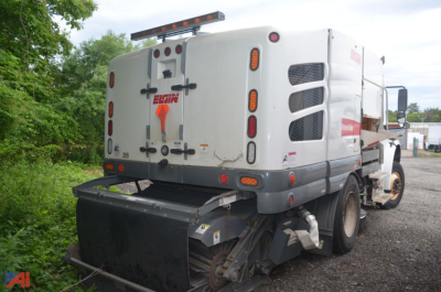 Front view of a 2017 Freightliner M2 106 sweeper showing rear body and dust/sweeping equipment, Elgin branding on rear hatch, ladder and safety lights.