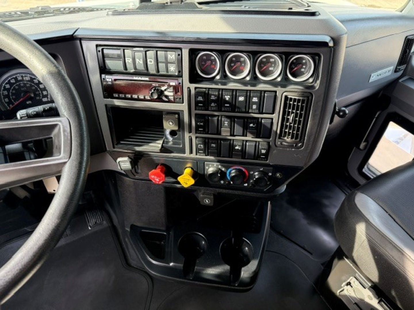 Dashboard and steering wheel of a 2020 Mack Anthem truck interior showing instrument cluster,control panels, switches, and knobs.