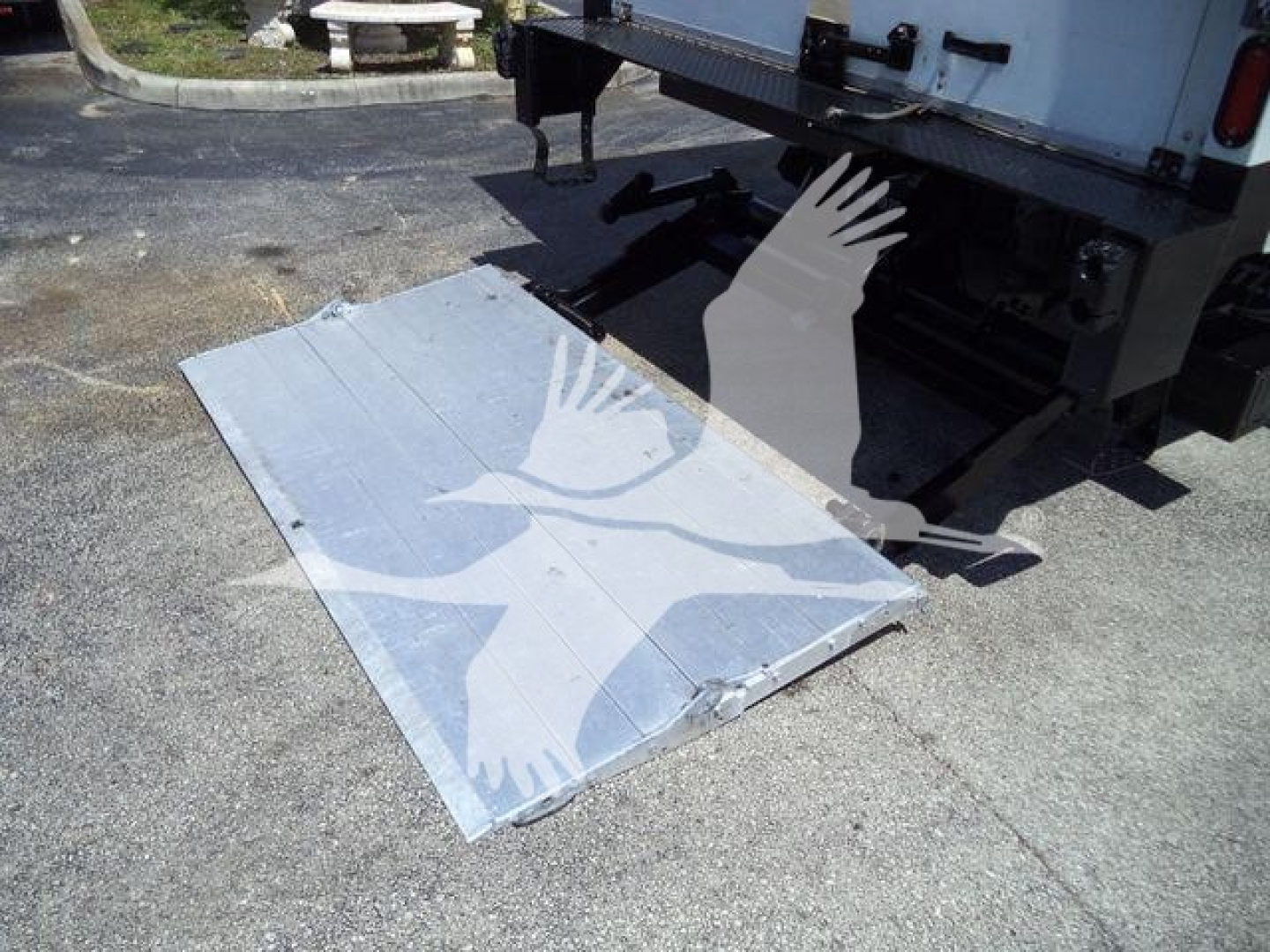 Isuzu NPR-HD box truck with lowered aluminum handicap ramp/staircase platform attached to rear. Side view shows tail area and underside frame.
