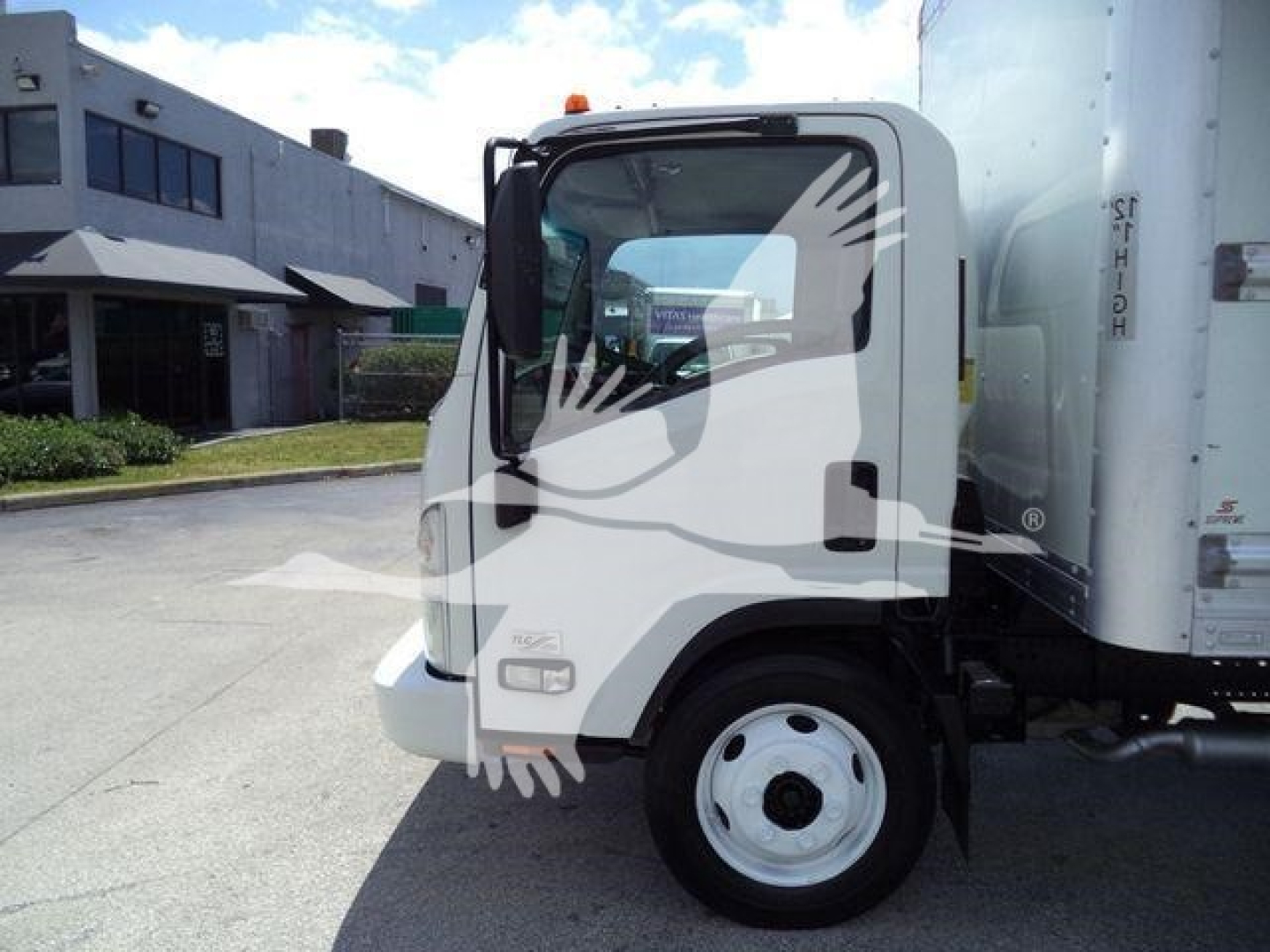 Isuzu NPR HD box truck cab side view showing mirrors and front wheel