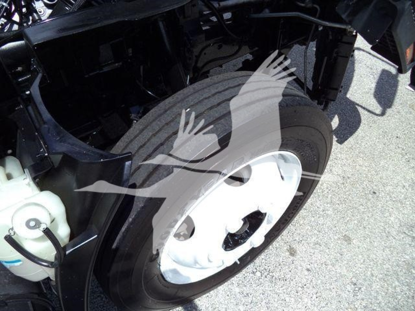 Isuzu NPR HD front wheel and suspension area in service bay showing wheel and tire
