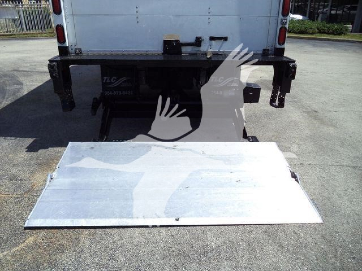 Isuzu NPR HD truck rear view with a deployed aluminum ramp/step and back bumper mounting hardware visible.