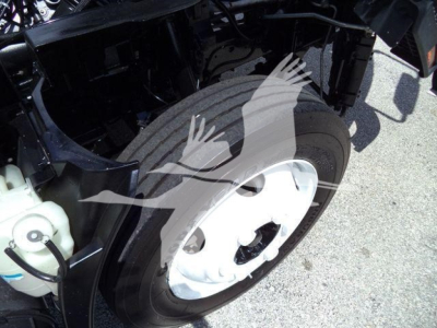 Isuzu NPR HD front wheel and suspension area in service bay showing wheel and tire