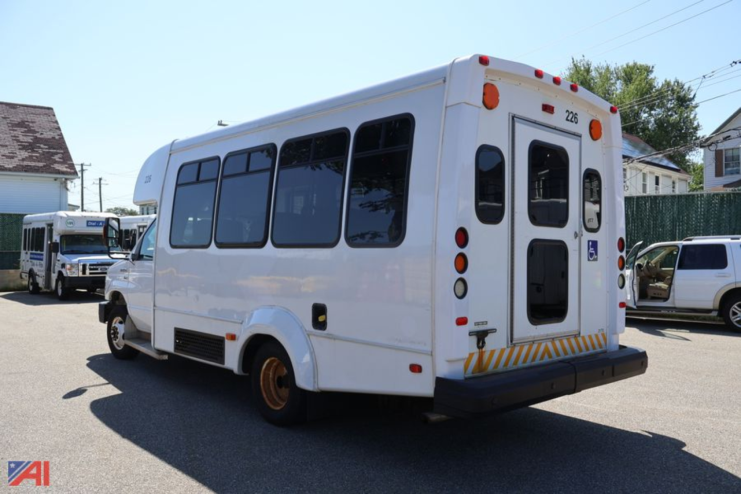 Ford E-350 shuttle bus rear-left view showing wheelchair access door and windowed side panels.