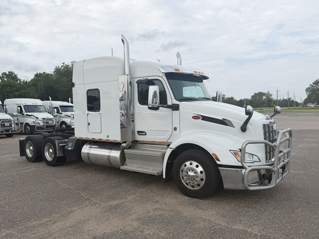 Peterbilt 579 UltraCab tractor in white, side view, with chrome bumper guard and dual rear axles, daytime outdoor lot.