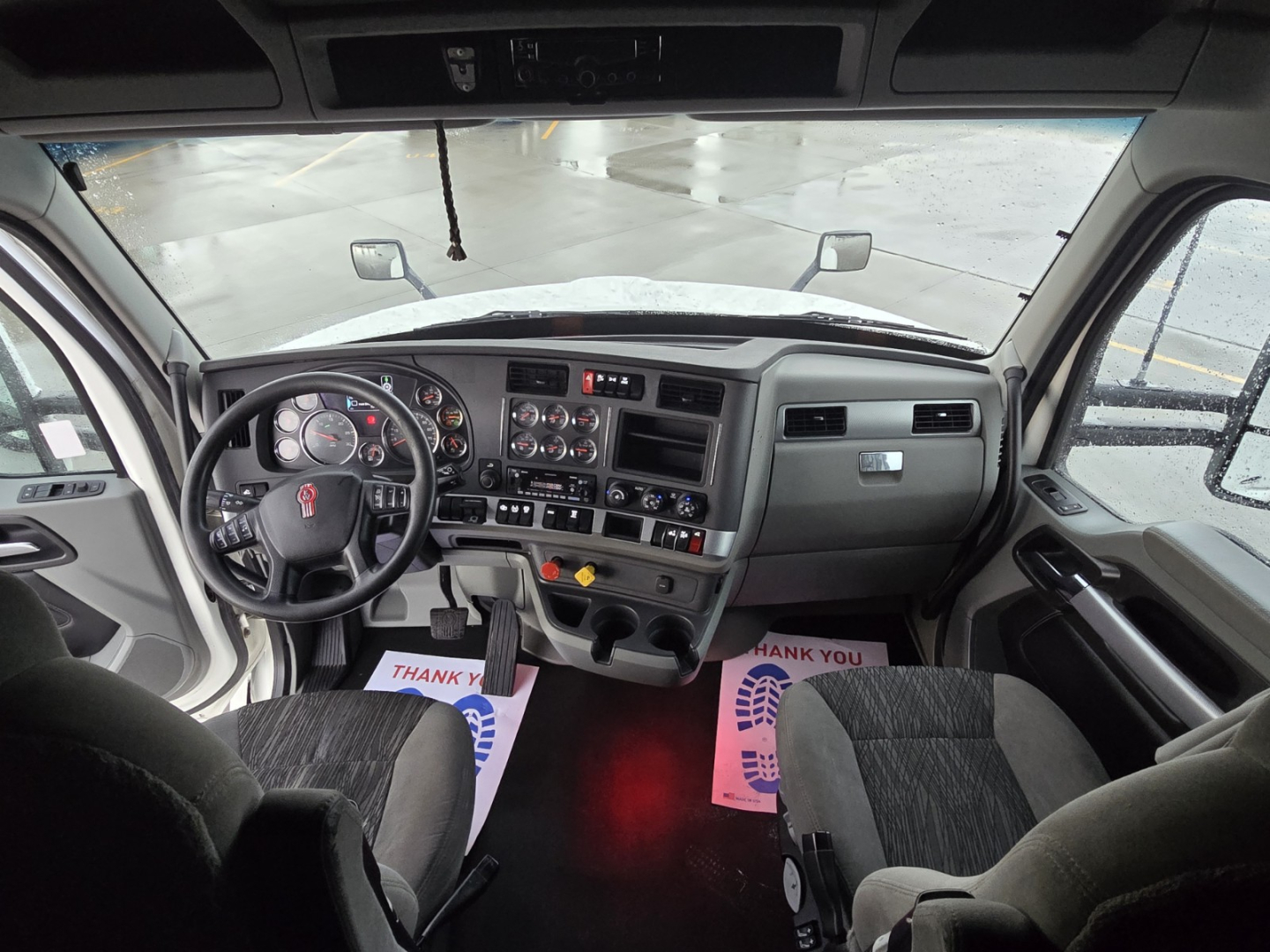 Kenworth T680 interior cab dashboard and steering wheel view from driver seat showing gauges and controls.