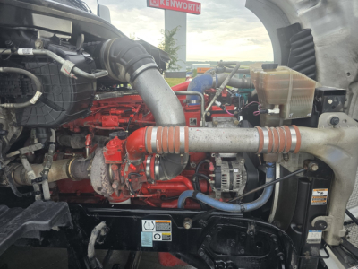 Kenworth T680 engine bay showing intake hoses and red engine components with surrounding black chassis.