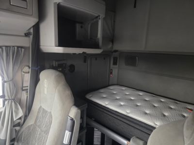 Kenworth T680 sleeper cab interior with bunk bed and driver's seat visible.