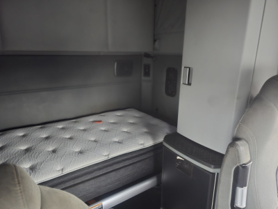 Kenworth T680 sleeper cab interior showing a bed with mattress, storage cabinet, and side panel in cabin