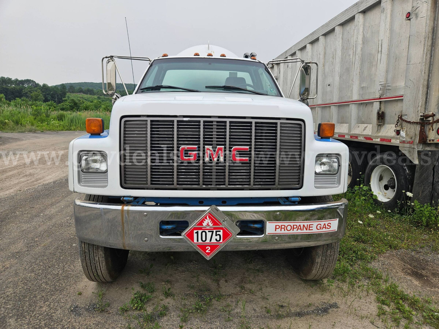 GMC C7500 front view showing grille with red GMC letters and propane gas diamond placard below bumper.