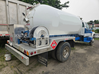 GMC tank truck with cylindrical tank mounted on chassis showing rear hazard placard 1075 and tank access fittings.