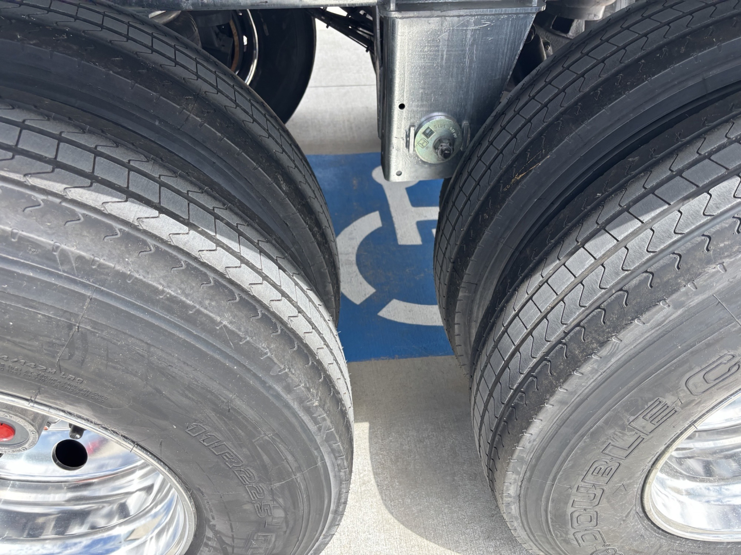 Trailer axle with dual tires and blue hoist tag visible between wheels.