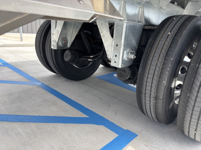 Trailer axle and dual wheels showing aluminum grain hopper trailer undercarriage and suspension components.