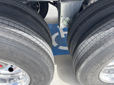 Trailer axle with dual tires and blue hoist tag visible between wheels.