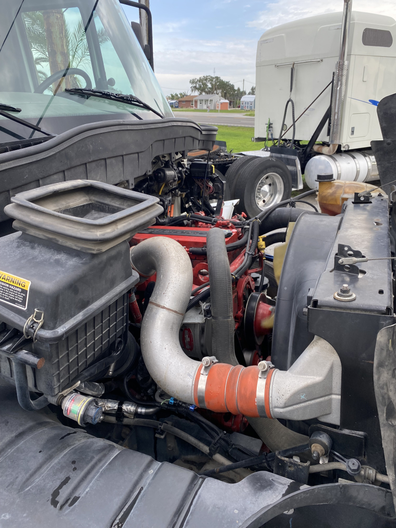 Diesel engine bay of a 2018 International 4300 truck showing intake piping, intake air filter housing, and turbo/intercooler piping.
