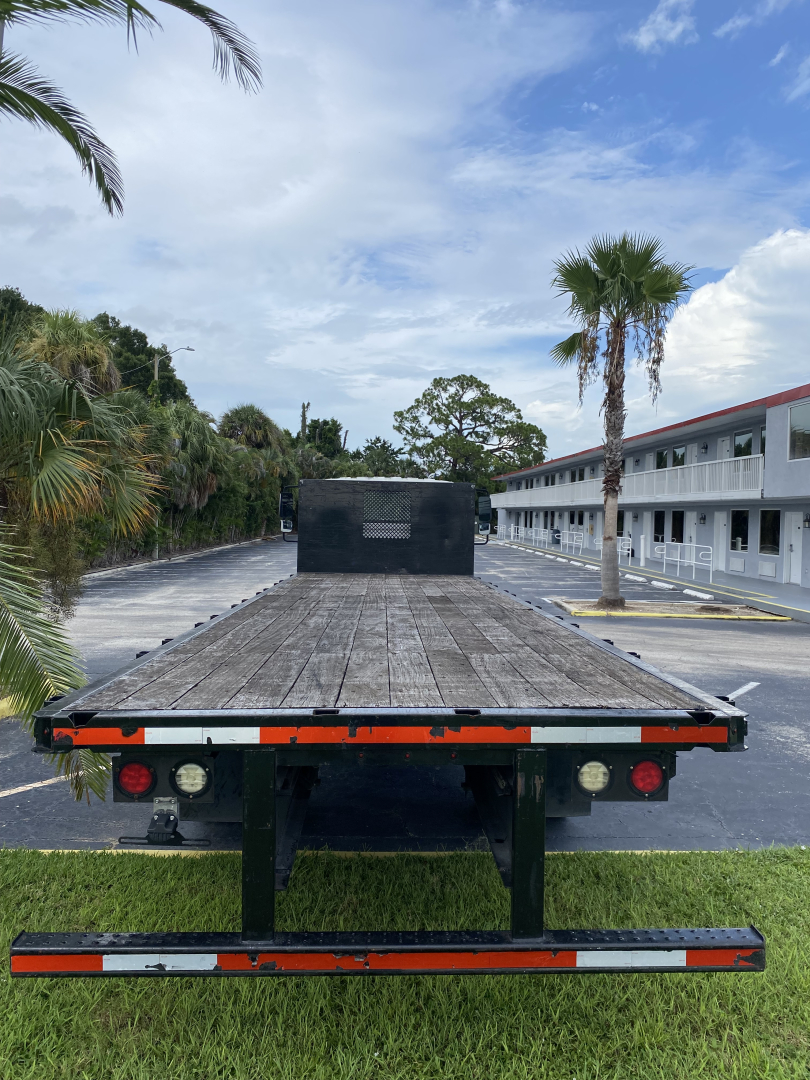 Flatbed truck trailer rear with black toolbox and red reflectors, International 2018 flatbed in a parking lot.