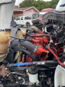 Engine bay of a 2018 International 4300 truck showing red engine components, hoses, and fluid reservoirs in view.
