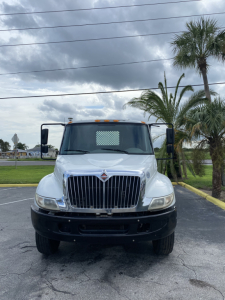 Front view of a white 2018 International 4300 truck with large grille, bumper, and side mirrors in a parking lot.