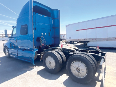 Blue International LT625 sleeper tractor front three-quarter view showing dual rear axle configuration and cargo area.