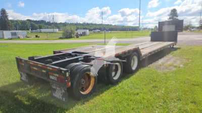 Trail King Tk90ed482 lowboy trailer showing dual rear axles and flatbed with ramp at back and spare tire area.