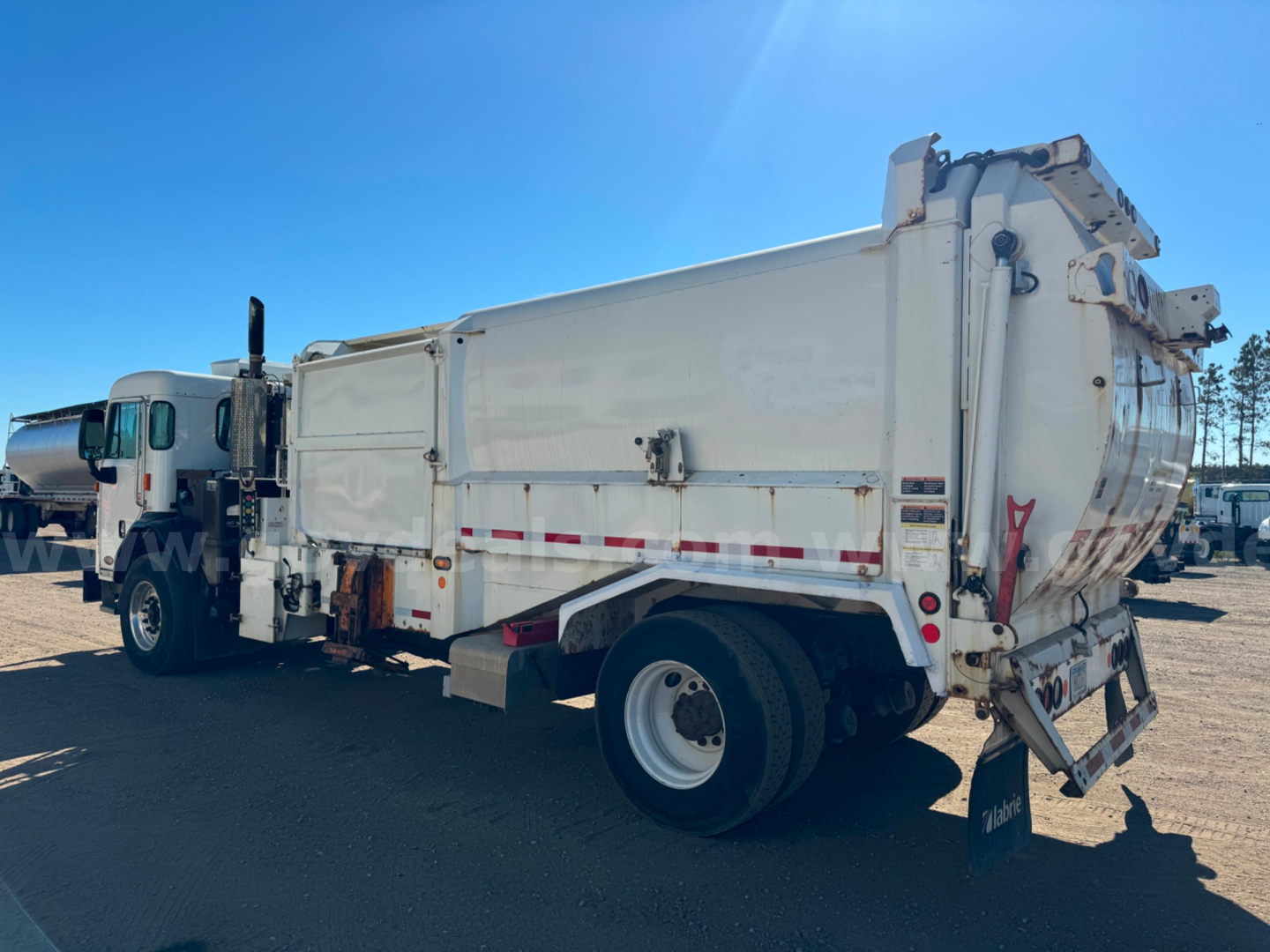 Peterbilt PB520 dump truck side rear showing cargo bed and chassis with white paint and reflective strips.