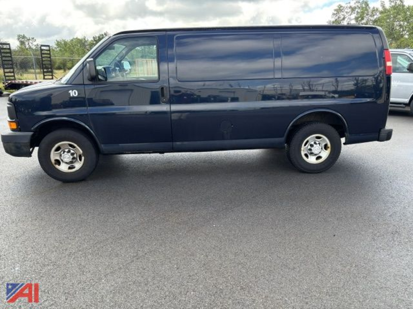 Vinyl-wrapped blue 2015 Chevrolet Express Cargo Van side view showing front cab and long cargo area with white wheel hubs.