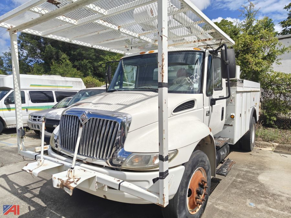 Bucket truck body on International 4300 with metal rack and platform in front view showing utility truck with white cab and equipment frame