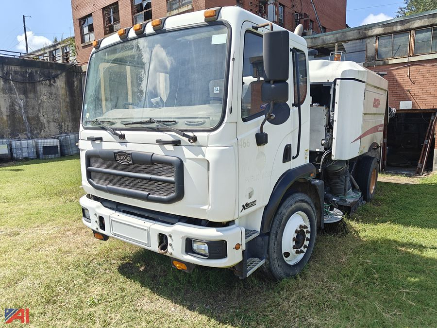 Autocar Xpert Sweeper truck front view showing cab and sweeping unit, clear windshield, side mirrors, and warning lights on the cab roof.