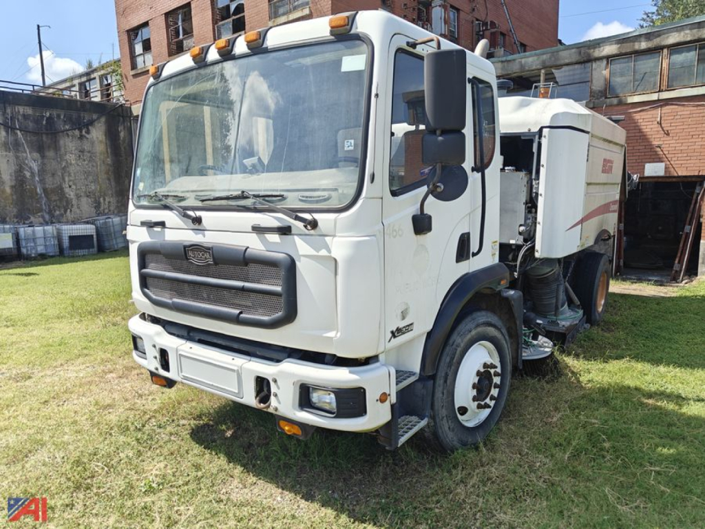 Autocar Xpert Sweeper truck front view showing cab and sweeping unit, clear windshield, side mirrors, and warning lights on the cab roof.