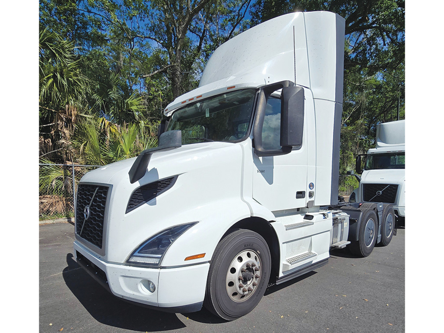 Volvo VNR 300 tractor cab in white, side view with sleeper, front grille and headlights visible, towing trailer behind.