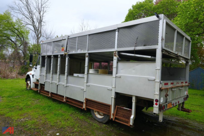 Dump truck side and rear view showing large metal cargo bed with tall mesh sides and rear tailgate for a 40 cubic yard capacity.