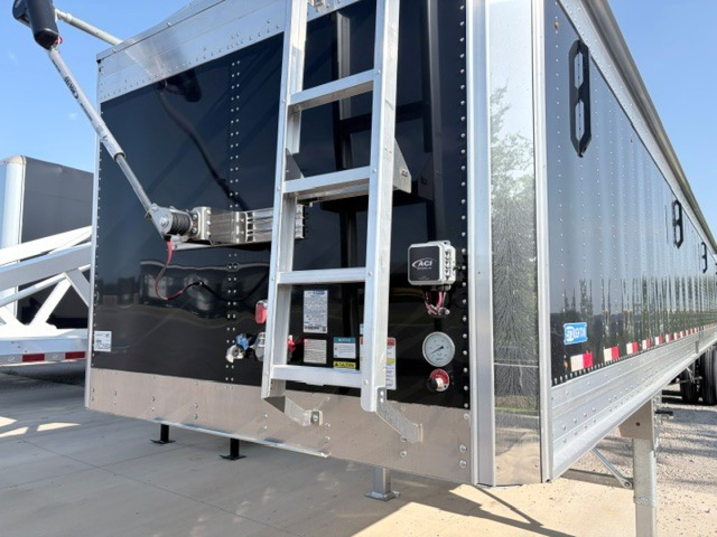 Stoughton 42' alum grain hopper trailer with black finish, 74" flat sidewalls, exterior ladder and access panel. Visible components: rear entry ladder, side boards, hydraulic or reinforcement brackets, front landing gear area.