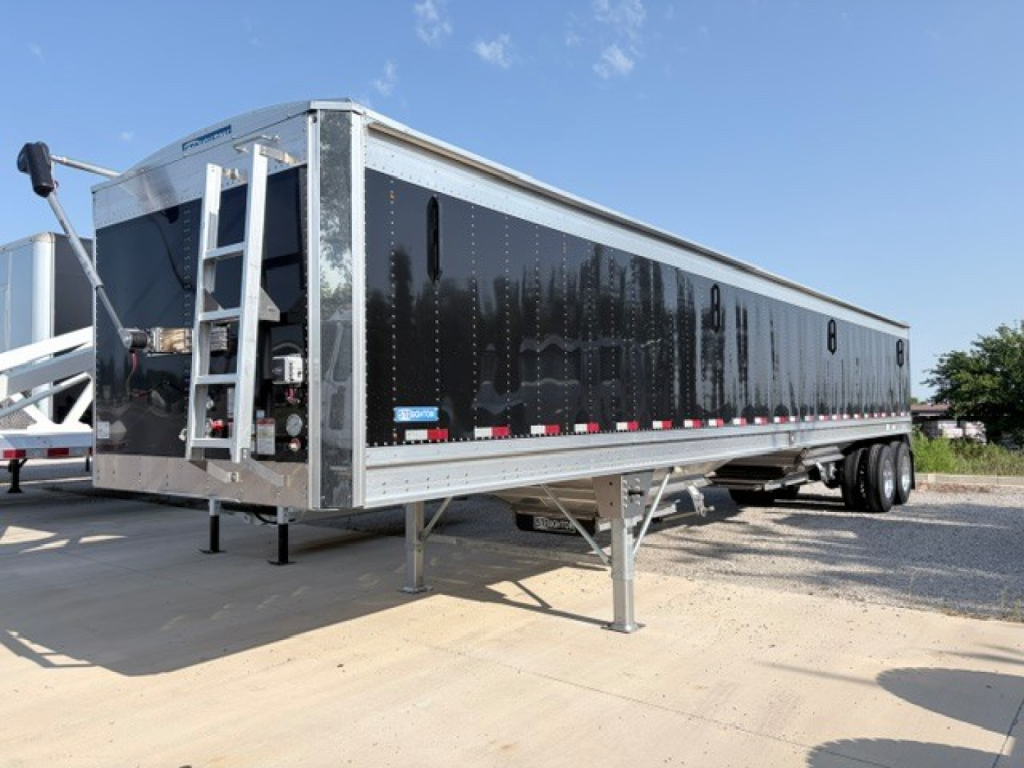Stoughton 42' aluminum grain hopper trailer with black exterior, 74" flat sidewalls, parked on gravel. Front access ladder and hitch visible, dual tandem axles, VIN tag area not legible.