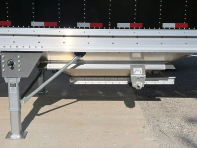 Trailer underside showing landing gear, frame, and sidewall reinforcement with a manual jack and support bar.