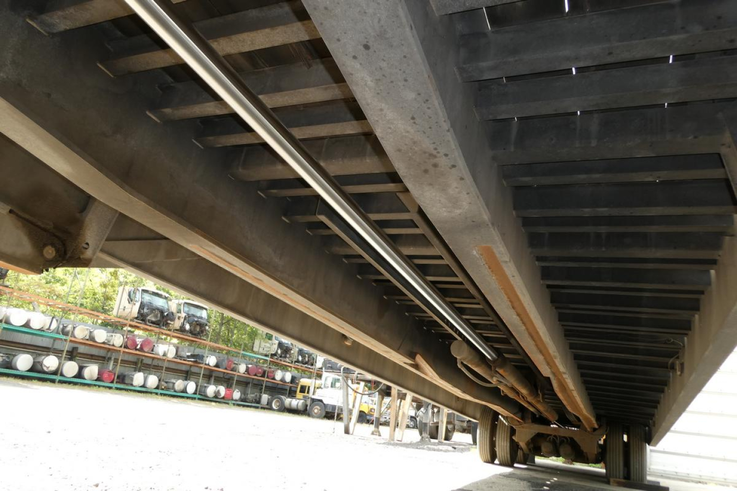 Trailer underside showing structural beams and support frame with hydraulic lines and undercarriage components.