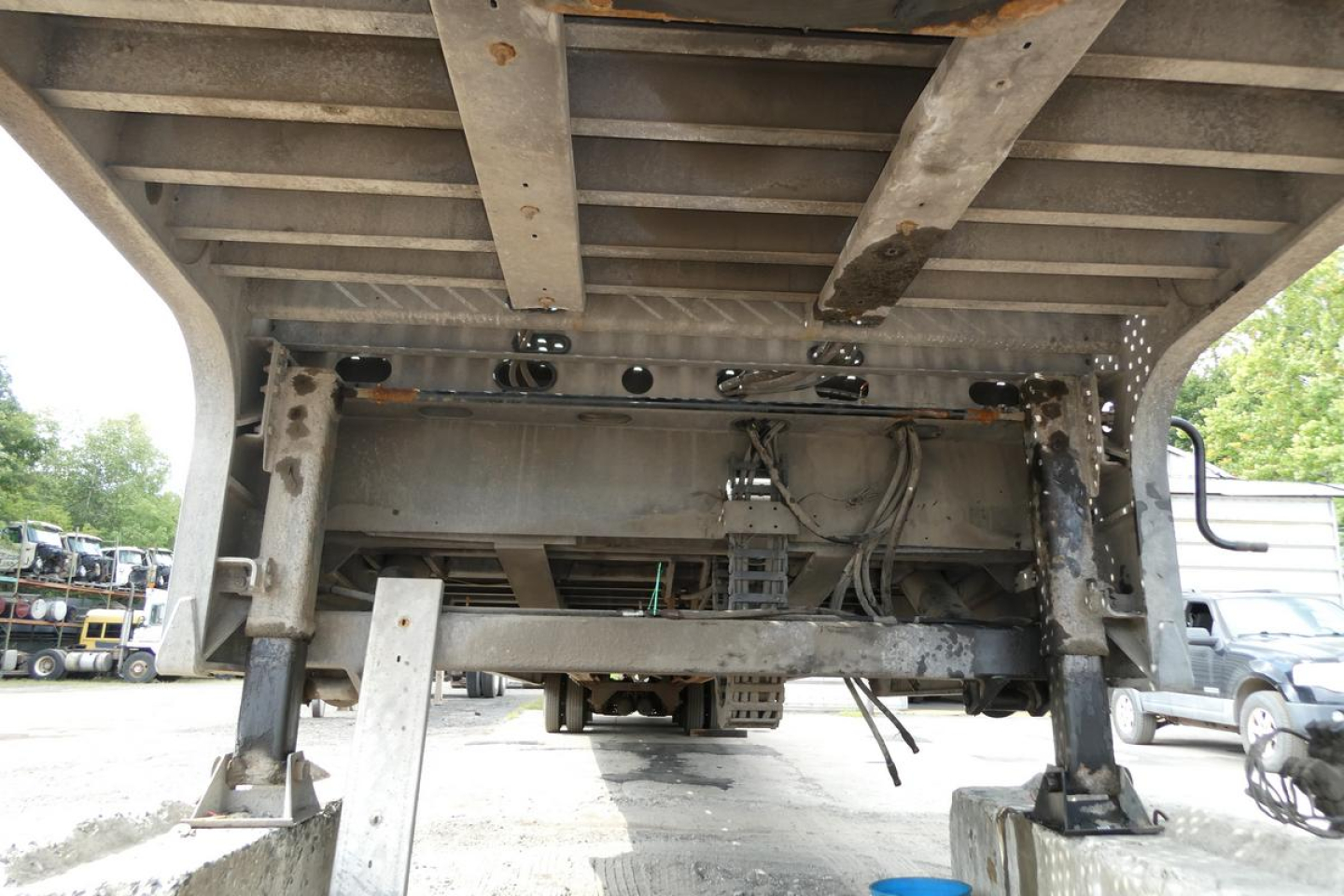 Underbelly view of Landoll trailer showing steel frame, suspension with multiple crossmembers, and hydraulic lines