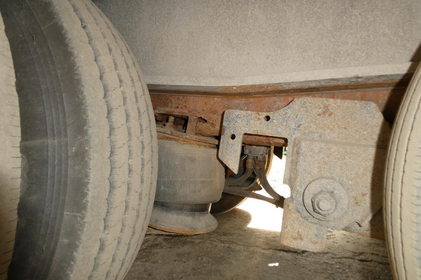 Underframe view of a trailer showing suspension components and leaf springs between dual tires.