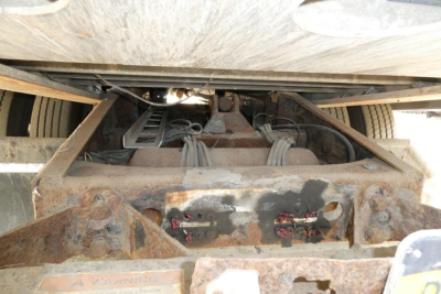 Trailer underside showing suspension and hitch components with rusted frame and wiring harnesses.