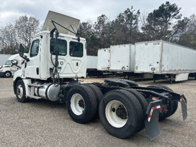 Freightliner Cascadia126 tractor-trailer cab (daycab) in-service showing rear chassis and dual rear axles with empty trailer at yard.