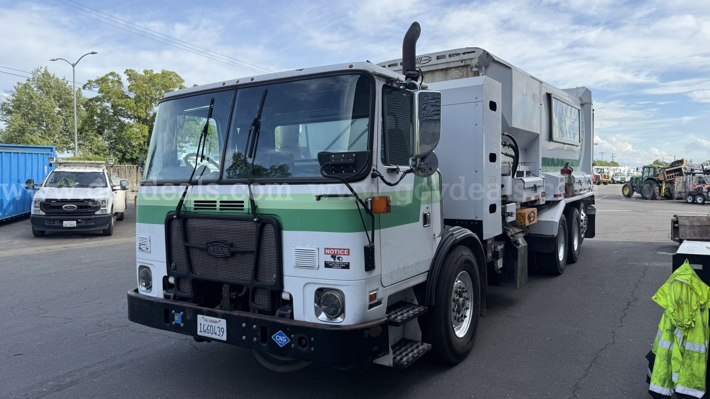 Autocar XPeditor truck with green stripe showing front view and cargo body in yard.