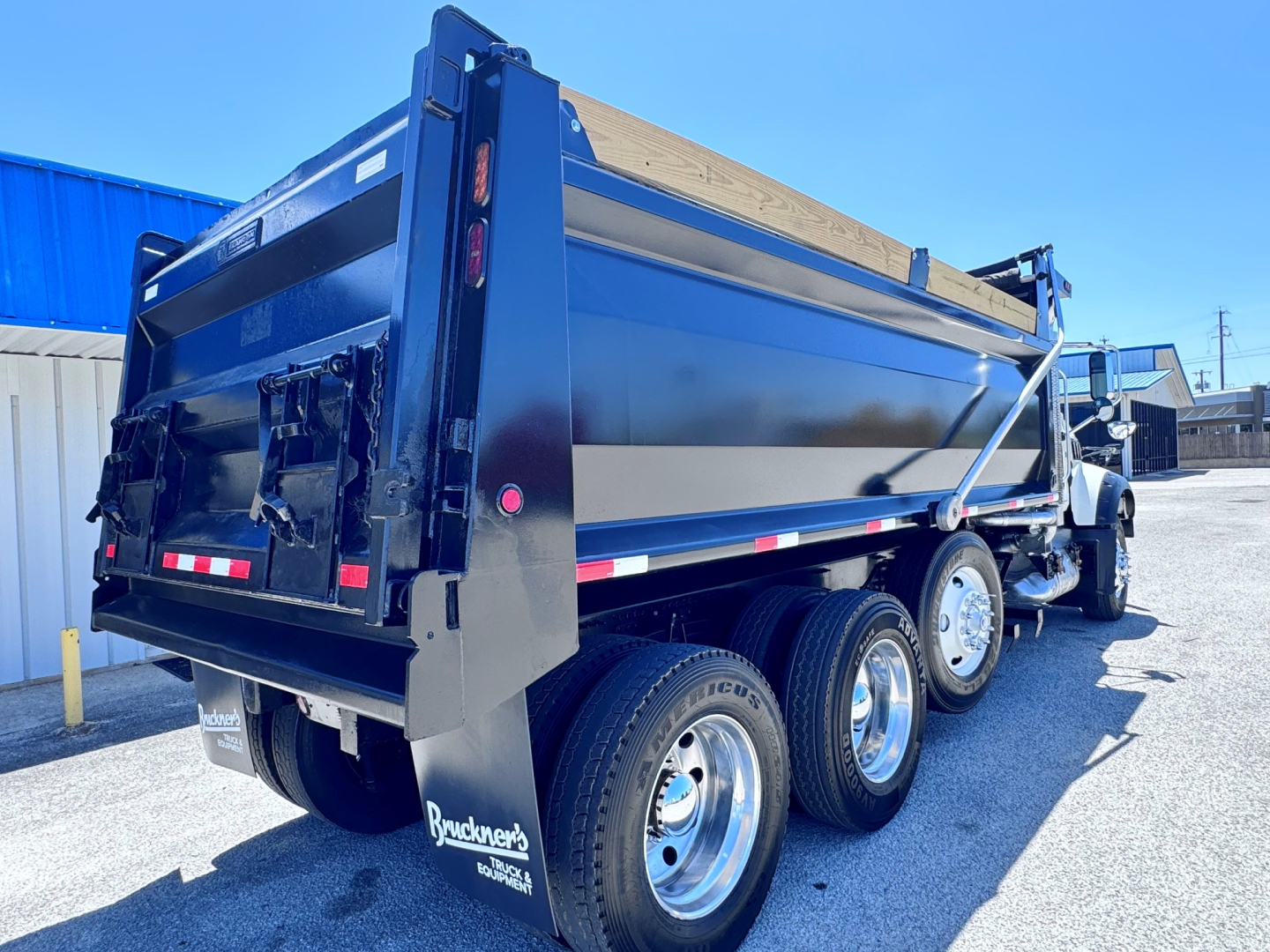 Dump truck bed of a 2023 Mack GR84F with triple rear axles, black painted dump body, rear tailgate and hydraulic hoist visible.