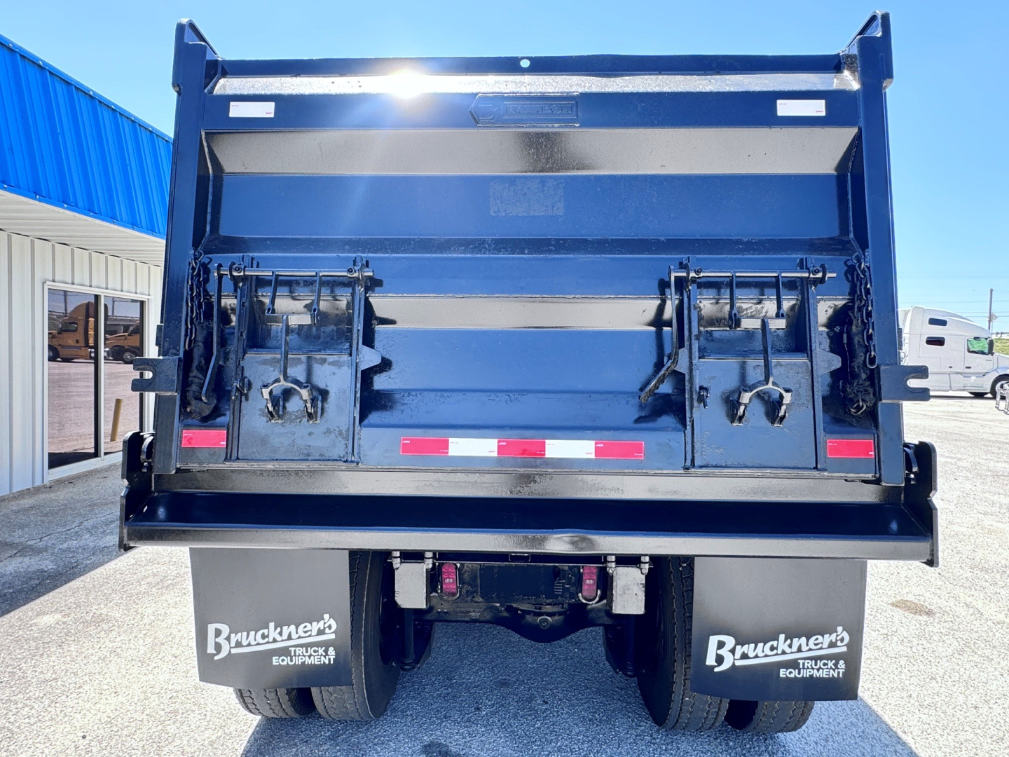 Dump truck bed of a 2023 Mack GR84F showing the tailgate with hydraulic latches and rear mud flaps labeled Bruckner’s Truck & Equipment.