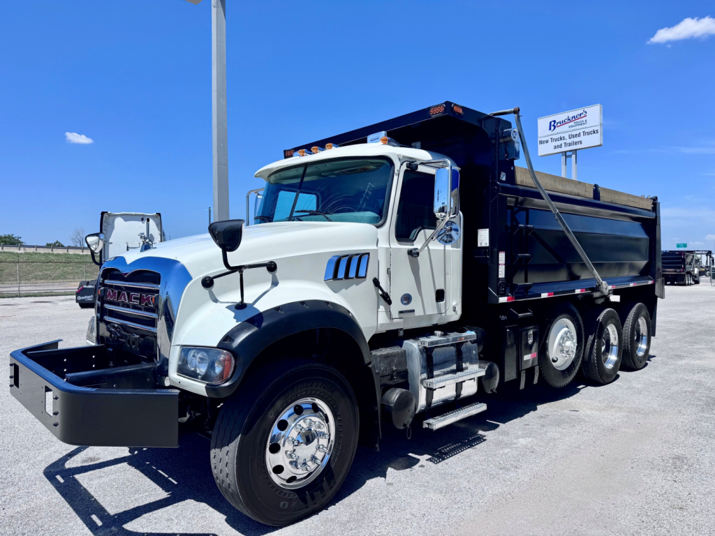Dump truck with white cab and black dump bed showing Mack GR84F series truck and front bumper guard.