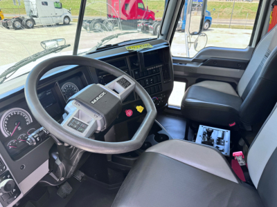 Truck cab interior of a 2023 Mack GR84F showing steering wheel, dashboard with gauges, and center console; visible VIN and stock context in background.