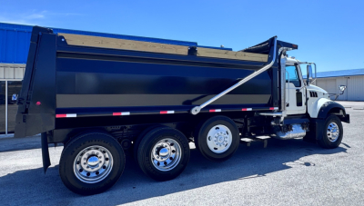 Mack GR84F dump truck in service showing black dump body and chrome wheels