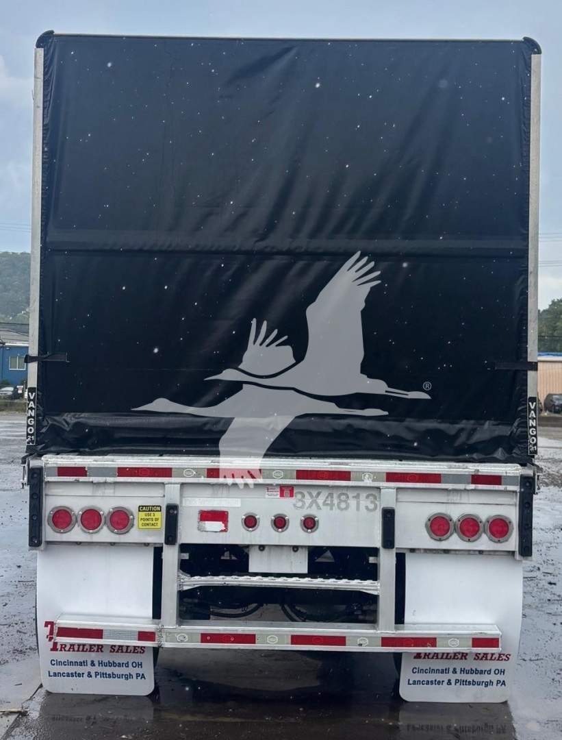 Mac aluminum flatbed trailer showing large black curtain with white logo and rear bumper lights.